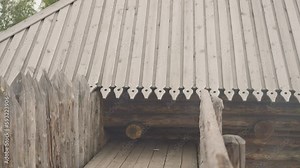 Traditional log house with fence and viewing platform. Wooden building with carved roof for residence of people of Middle Ages. Historical architectural object