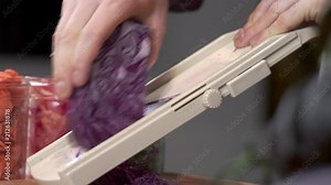 Dolly shot of chef slicing fresh red cabbage using mandolin