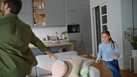 clip-4006505545-playful-daughter-running-father-modern-living-room