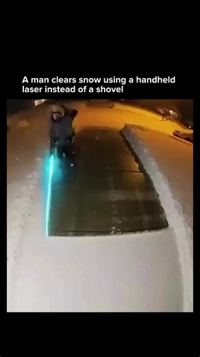 A man clears snow from his driveway using what appears to be a handheld laser based tool instead of a shovel or blower. The beam rapidly heats the surface causing the snow to melt and vaporize on contact, leaving the ground clear without physical effort. While it looks futuristic, the concept relies on concentrated thermal energy directed precisely at the snow layer. By converting electrical power into intense localized heat, the device removes snow without mechanical contact, showing an experim