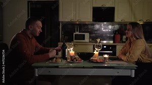 romantic candlelight dinner at home. A man and a woman sit at a table on a date to celebrate valentine's day on february 14 or anniversary.