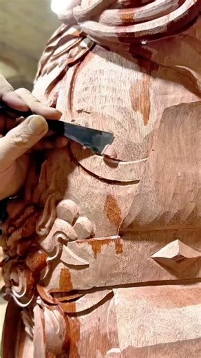 Carving intricate details on wooden statue using sharp chisel