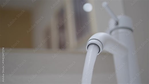 Water flows from a modern kitchen faucet in a home