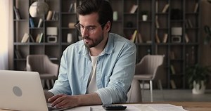 Focused serious man sit at desk working calculate costs using calculator laptop app, pay through e-bank application. Business, household expenses, accounting, managing finances, check incomes concept