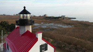 Slowly backwards flying drone shows a historic lighthouse.