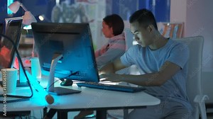 Young mixed ethnicity computer game design team working together in dark office