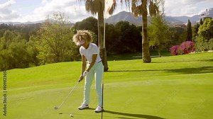 Woman golfer putting for the hole and flag on a lush green tropical golf course