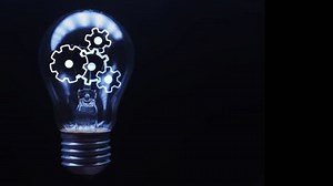 Rotating gears inside a light bulb in which the light turns on and off on a black background. Technological footage. Cg