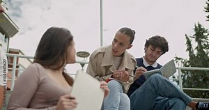 Students and professor discuss coursework after class. They sit outside on steps and review material together.