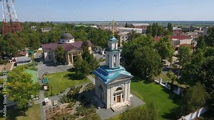A splendid aerial shot of a high orthodox church from a bird`s eye perspective in summer on a sunny day. It has a blue doom a golden cross and a nice park around it.