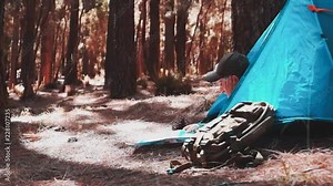 Couple of caucasian adult senior people lay down inside the tent camped in the middle of the forest. Alternative way ti live a vacation holiday with backpack and adventure over the mountains. Joy