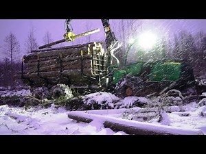 John Deere 1110E logging in snowy winter forest, skiled operator