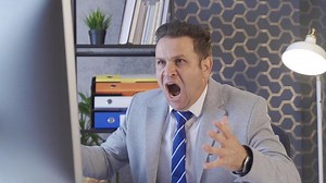 Unsuccessful office worker. Businessman looks at computer and gets angry.  Office worker man looking across, shouting, getting angry.