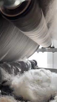 Our carding machine transforming fleece into the soft, lofty fiber used in our needle felting kits.