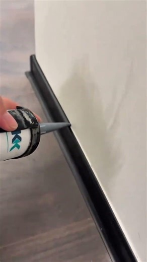 applying white silicone sealant to the edge of a wall using a caulking gun for neat finishing