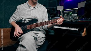 in the recording room equipment the sound of music a handsome young guy plays an electric guitar plucks the strings choosing the right note