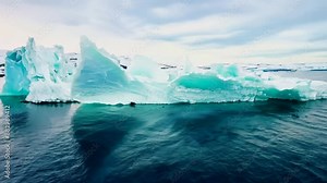 Drone footage capturing the iceberg collapse, with large pieces of ice falling and creating huge splashes.