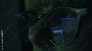 Hacker wearing Glasses Working on Computer, Code is reflected in his eyes and on the glasses, Software Developer NumProgrammer works on computer screen committing cybercrimes. Close up of face dark
