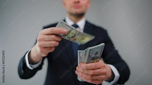 Formally dressed man carelessly throws US Dollar bills towards the camera