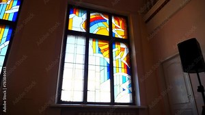 Colourful stained glass window with intricate designs in church. Sunlight filtering through ornate stained glass window. Depiction of religious figures in radiant stained glass window.
