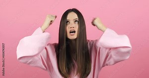 Close up of annoyed irritated young woman with an angry face looking furious, mad and feeling frustrated isolated on pink background. Brunette girl expressions and emotions.