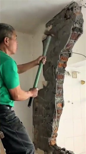 Wall demolition process using manual tools to remove old bricks during home renovation