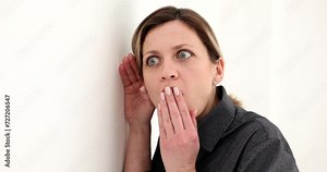 Portrait of woman eavesdropping on private conversations behind wall. Manager spying and eavesdropping through wall with shocked expression
