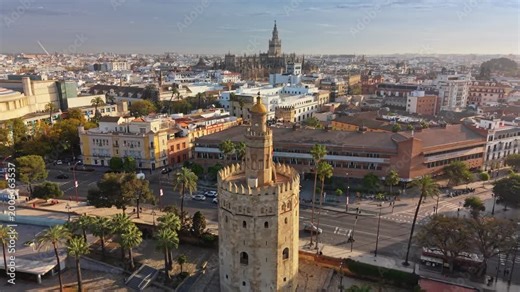 Beautiful aerial reveal of the Torre del Oro and Seville Cathedral at sunrise, Seville, Spain. historic center of Seville featuring the grand cathedral and Giralda tower