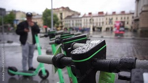 Electric scooters for rent parked in a row in the city. Ecological transportation. Man scaning qr code and taks electric scooter to get around the city.