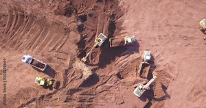 Top down view of several excavators working on a construction site. Heavy industrial machinery. Excavators loading Articulated hauler Trucks.