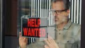 A small business owner, putting up a help wanted sign in her store...