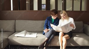 Two female friends reading newspaper news during sitting on a, girl pointing to newspaper and talking about something to her curious colleague. Mass media