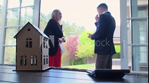 Real estate manager and businessman inspect house focus at wooden toy model. Real estate agent giving tour of sunurban cottage residence