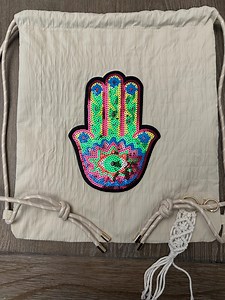 Drawstring bag with zipper pocket and evil eye design