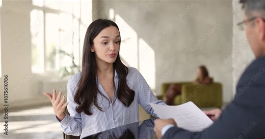 Young adult woman applicant presenting herself during job interview, explaining her experience, skills to HR manager listen and reviewing her documents. Human resources, candidate assessment, recruit