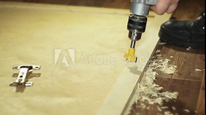 Close-up forstner bit drills wood. The joiner with manual electric drill cut a hole in the wooden door to install the hinges, slow motion.