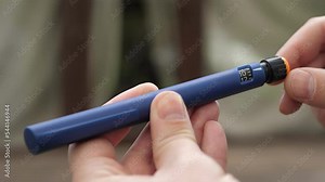 A diabetic man holding in hands a syringe pen with an insulin cartridge. A scale window on a syringe with a handle showing the number of dose units.Diabetes and prevention of diabetes complications