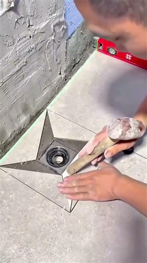 Installing ceramic floor tiles around drain with precise alignment for clean durable finish solid