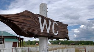 An outdoor wooden arrow signboard WC, public restroom sign in a countryside park
