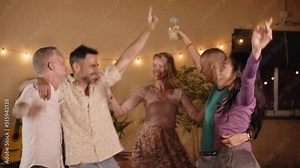 A group of mature friends celebrate dancing at a private party in the backyard or at a club. Happy and joyful people partying at an outdoor nightclub.