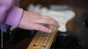Get started on musical instruments, baby testing electric guitar vibrating string close up