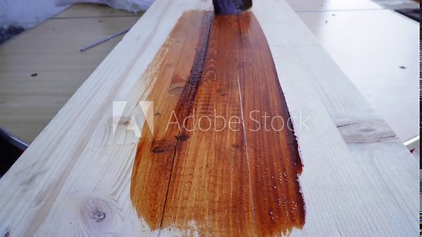 Applying varnish to wood with a brush. Wood coating and protection. Manual labor