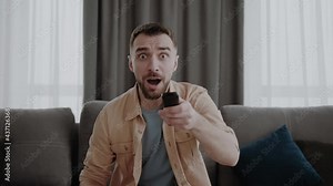 remote controller in male hands, happy young man switching channels on smart tv, choosing film for comfort evening domestic pastime or watching funny programs or series alone at home.