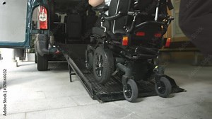 Wheelchair going into vehicle using ramp. Driver is helping to push it up.