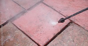 High angle shot of cleaning a flagstone with high pressure water jet. Flagstone changes from dirty to clean, revealing the beautiful original red color.
