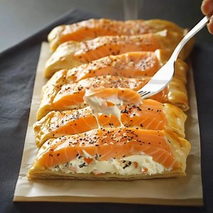 Feuilletés au Saumon et Fromage Ingrédients: 1. 1 pâte feuilletée rectangulaire 2. 200 g de saumon (frais ou fumé, en tranches) 3. 100 g de fromage frais (type Philadelphia ou équivalent) 4. 1 cuillère à soupe d'aneth ou de ciboulette, ciselée 5. 1 œuf, pour la dorure 6. Sel et poivre, au goût Directions: 1. Préchauffez le four: 1.1. Préchauffez votre four à 180°C (thermostat 6). Tapissez une plaque de cuisson de papier sulfurisé. Préparez les Feuilletés: 2.1. Déroulez la pâte feuilletée et coup