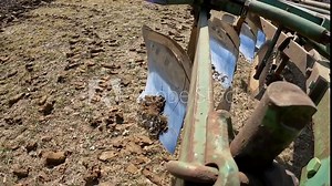 Close up of plow chisel when farmer raises the plow to turn into a new row in the field; Farmer prepares field for planting in early spring in Midwest; concepts of farming and land management