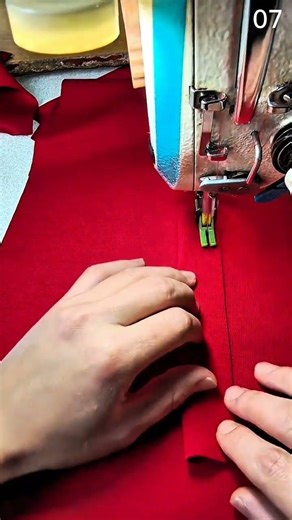 Guiding red fabric through sewing machine with steady hands