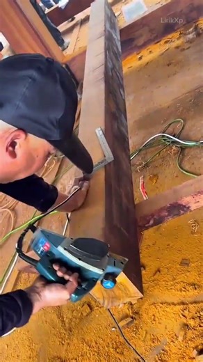 using an electric hand planer to smooth the surface of a large wooden beam while measuring carefully