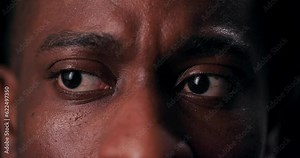 A haunting close-up shot of an African American man's terrified eyes sends chills down the spine, conveying the raw fear and vulnerability of the human experience.